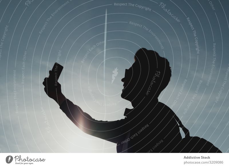 Silhouette eines Mannes mit Telefon gegen den Himmel Selfie tausendjährig Smartphone Technik & Technologie Mobile männlich modern Sonnenlicht hell sorgenfrei
