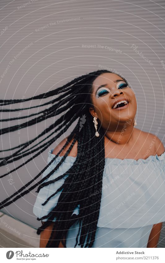 Fröhliche, trendige afroamerikanische Frau mit fliegenden Haaren fliegendes Haar Glück trendy Lächeln modern attraktiv Zopf umdrehen Straße Inhalt stehen