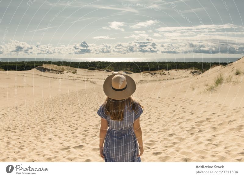 erwachsene Frau in Freizeitkleidung und Strohhut stehend, die sich auf einer Sanddüne vergnügt Sommer verträumt Düne heiß Tourismus modern Klarer Himmel Kleid