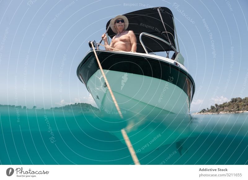 Mann segelt im Boot in klarem türkisfarbenen Wasser Segeln Jacht älter Urlaub Sommer nautisch reisen MEER Reichtum Freizeit halkidiki Matrosen Griechenland