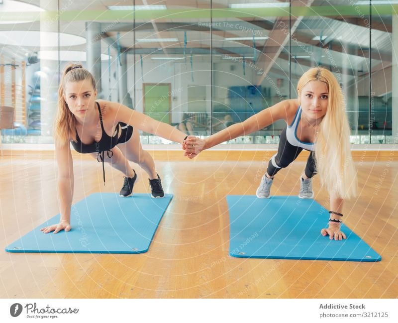 Junge Sportlerinnen auf dem Seitenbrett Athlet Übung Schiffsplanken Fitnessstudio Arme Team heben Frauen Wellness Training Zusammensein Gleichgewicht abstützen