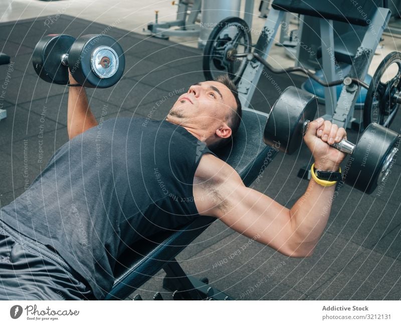 Starker Mann übt mit Hanteln auf der Bank Athlet Kurzhantel Lügen heben Presse Übung Bodybuilding Fitnessstudio fokussiert Motivation Ausdauer männlich Training