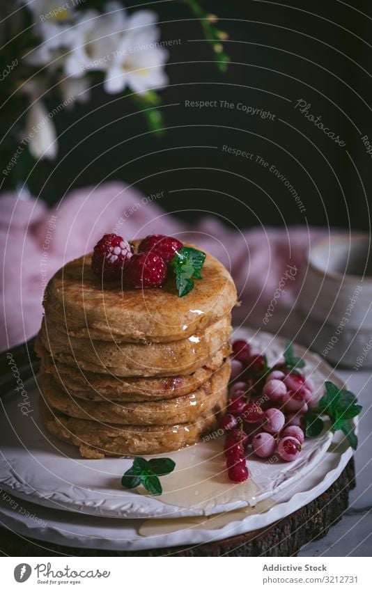 Stapel Himbeerpfannkuchen mit Honig auf dem Teller Pfannkuchen Himbeeren frisch Haufen gold-braun Liebling Murmel Porzellan Tischplatte Blumen Frühstück