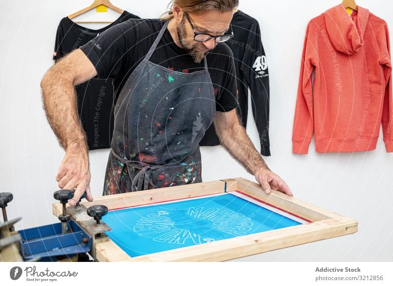 Künstlerischer Siebdruck in der Werkstatt Bildschirm drucken T-Shirt Kunstwerk Meister Hobby Serigraphie kreativ Staffelei Malerei Zeichnung männlich