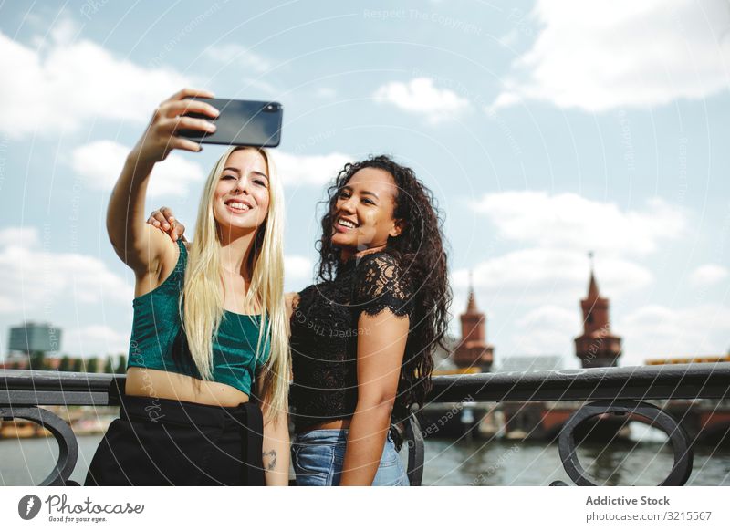Freunde, die an einem sonnigen Tag Selbstgefälligkeit zeigen Frau Selfie Berlin Telefon heiter Lächeln jung multiethnisch Zusammensein rassenübergreifend schön