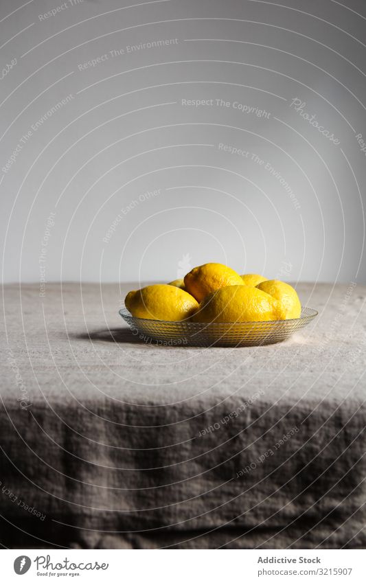 Reife, saftige Zitronen im Teller auf dem Tisch Zitrusfrüchte Lebensmittel frisch reif Glas grau Leinen gelb sauer glänzend roh organisch natürlich
