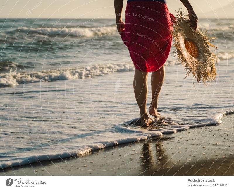 Frau mit rosa Pareo am Sandstrand Ernte Strand anonym unkenntlich horizontal Rückansicht sandig Badebekleidung pareo Hut Wasser laufen Meer Sommer genießend