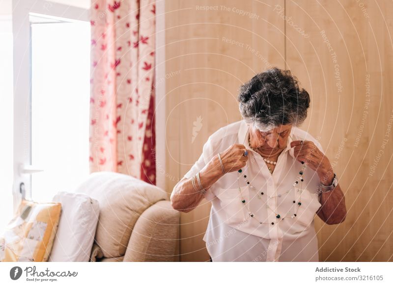 Ältere Frau, die zu Hause in der Nähe eines Sessels steht gealtert heimwärts Großmutter Weisheit Aufmerksamkeit Großeltern Generation Senior älter Hautfalten