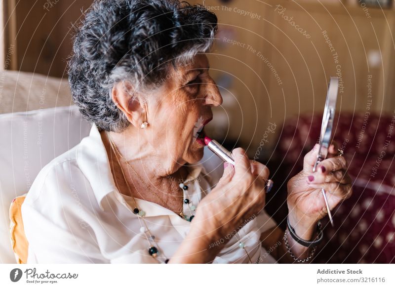 Ältere Frau schminkt ihre Lippen zu Hause gealtert Großmutter Make-up heimwärts Erfahrung Weisheit Pflege Schönheit Senior älter Hautfalten Oma grauhaarig