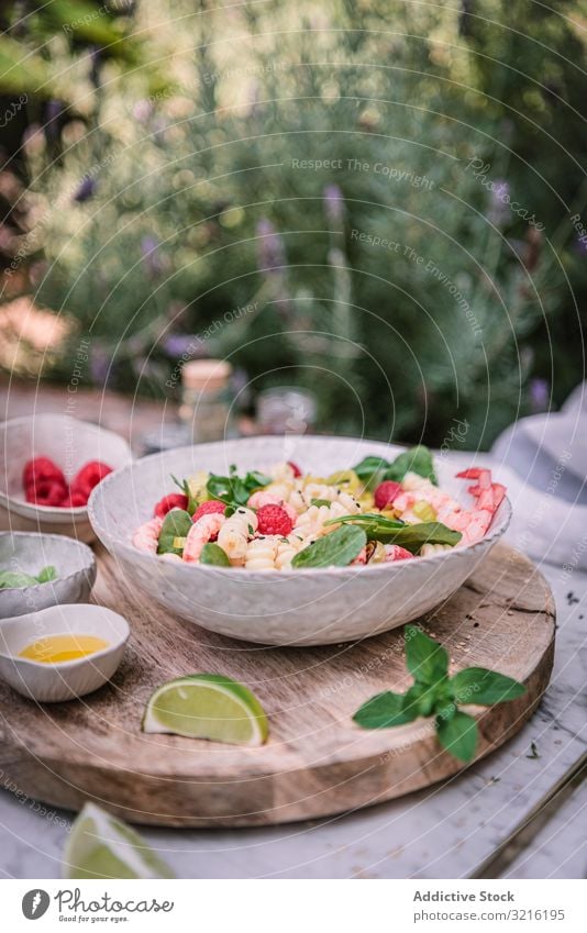 Schmackhafter Salat auf Holzständer, serviert auf dekoriertem Tisch im Freien Salatbeilage geschmackvoll Mahlzeit Lebensmittel Gesundheit Abendessen Beeren Kalk