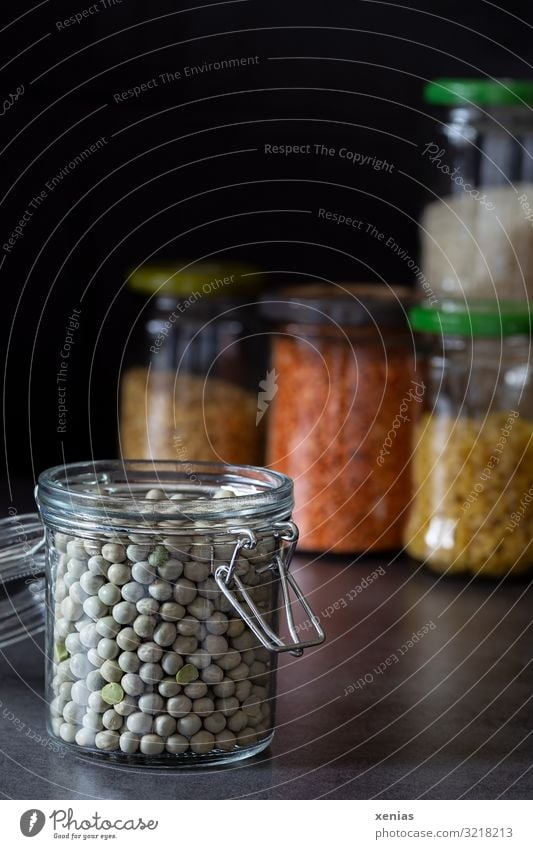 abgefüllte Erbsen in offenem Glasbehälter vor weiteren Vorratsgläsern Einmachglas Nudeln Linsen Bioprodukte kaufen modern retro Lebensmittel nachhaltig
