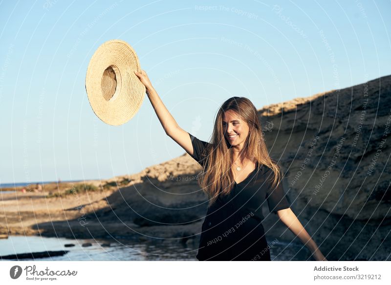Fröhliche Frau hält Hut in der Luft Model heiter Strand Natur Lächeln stylisch jung attraktiv schön hübsch Sommer natürlich elegant posierend reisen Tourist