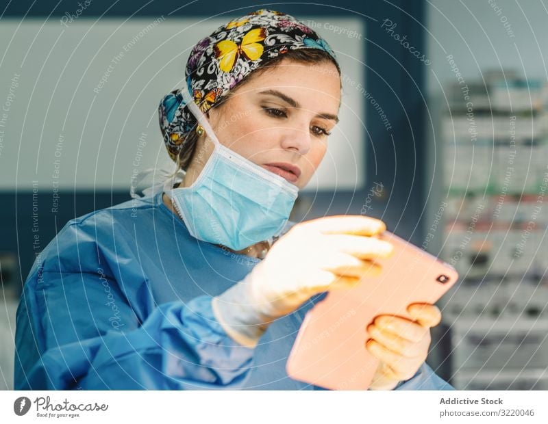Ärztin stehend mit Smartphone Chirurg fotografierend Frau Arzt Medizin Krankenhaus benutzend Operation Chirurgie Klinik jung ernst schön attraktiv konzentriert