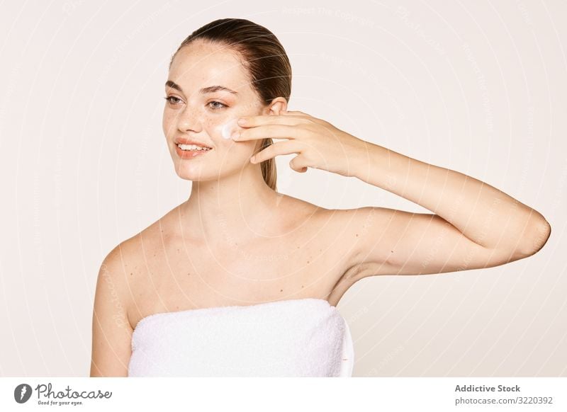 Liebenswürdige Frau kümmert sich um das Gesicht Pflege Haut Sahne Reichtum Kosmetik Kosmetologie zierlich freundlich rein Pose bewerben Körper Model nackt schön