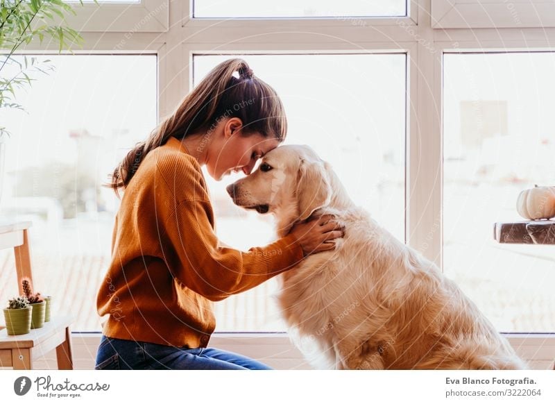 Schöne Frau, die zu Hause ihren bezaubernden Golden Retriever Hund umarmt. Konzept der Liebe zu Tieren. heimwärts Umarmen Lifestyle Innenaufnahme Zusammensein