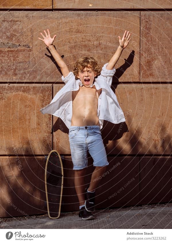 Fröhlicher Junge mit erhobenen Händen beim Skateboard Kind Skatepark Lifestyle heiter Schreien Sie Sport Hände hoch Freizeit Hobby jung Kindheit cool Interesse