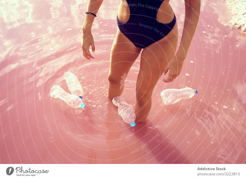 Schlankes Weibchen im Badeanzug steht in verschmutztem See mit Müll Verschmutzung Wasser Verunreinigung rosa Frau Mineral Salz Pool Kunststoff schwimmen