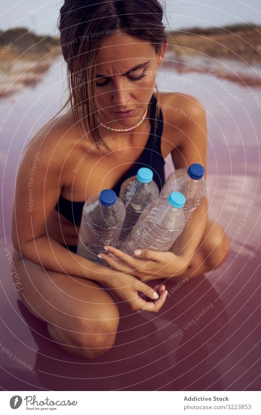 Besorgtes Weibchen im Badeanzug beim Müllsammeln im natürlichen See Verschmutzung Wasser Verunreinigung Frau abholen betroffen Pool pflücken Flasche Kunststoff