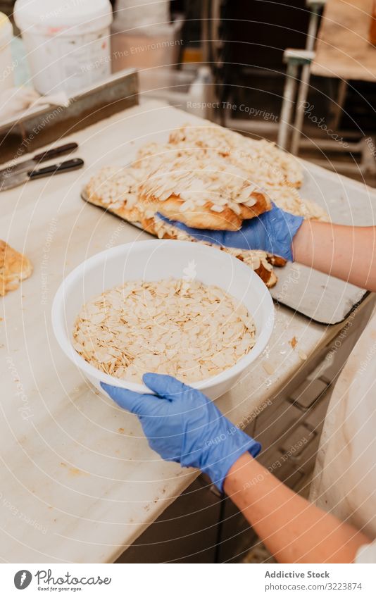Getreidebäcker, der Brötchen mit Mandelblättchen herstellt Konditor Koch Schuppen Küche Bäckerei frisch Schalen & Schüsseln Abfertigungsschalter Prozess