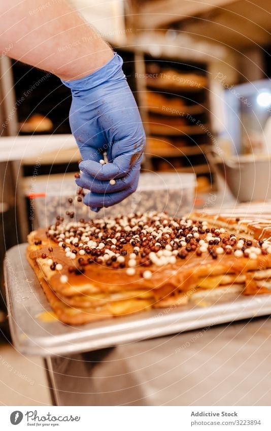 Anonymer Bäcker streut Streusel auf Gebäck Konditor Bäckerei Aufstrich Dekor Tisch Qualität Kuchen Vorbereitung Kleinunternehmen frisch Beruf traditionell