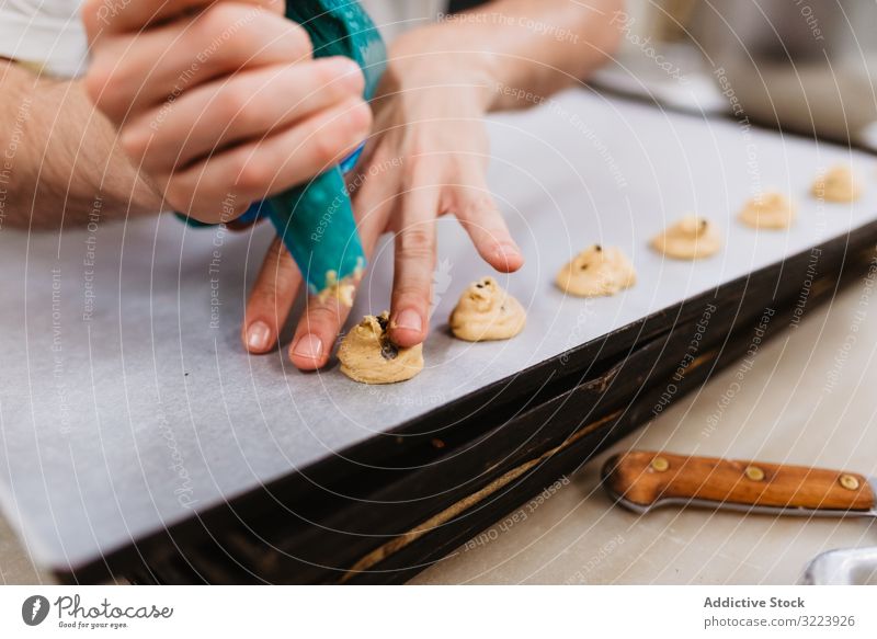 Erntebäcker, der Teig auf einem Blech auspresst Konditor Bäckerei Teigwaren drücken Tablett Keks Arbeit Küche Vorbereitung professionell Lebensmittel Papier