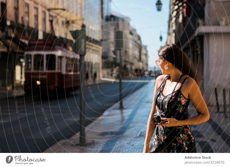 Frau, die eine Kamera hält, während sie auf der Straße steht Stadt reisen lässig Fotokamera selbstbewusst Bild malerisch Lissabon Portugal sonnig Großstadt