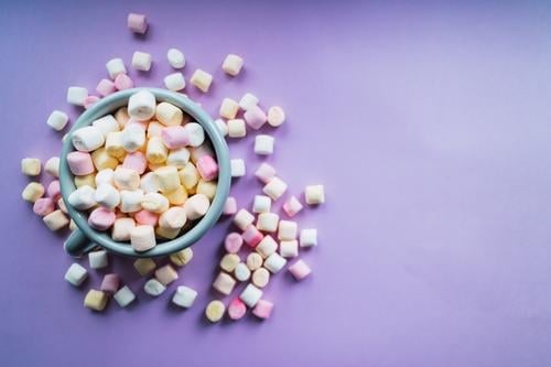 Heiße Schokolade mit bunten Marshmallows auf violettem Hintergrund. Dessert Getränk Winter Dekoration & Verzierung heiß weich gelb rosa weiß Farbe Zucker Tasse