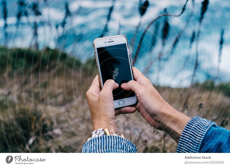 Person, die ein Smartphone benutzt, während sie an der Küste chillt reisen Seeküste MEER benutzend Drahtlos Touchscreen Nachrichtenübermittlung Apparatur Urlaub