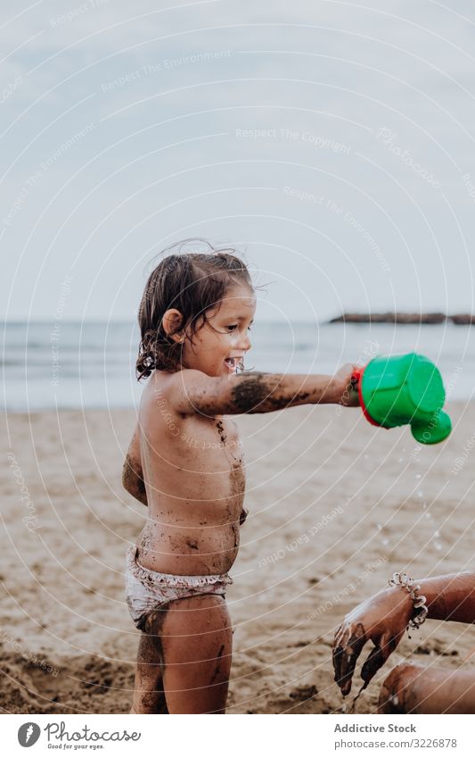 Lächelndes Mädchen spielt mit Wasser auf Sand spielen sandig Strand Gießen Bewässerung Sommer Gießkanne Urlaub Zusammensein Familie Kind Feiertag Spaß MEER