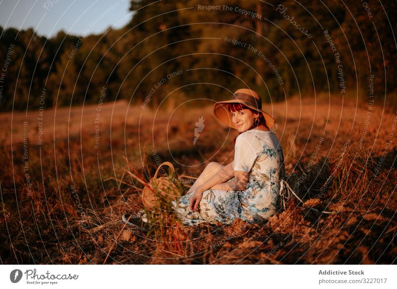 Frau auf dem Feld sitzend Sonnenuntergang retro Natur Abend Himmel Landschaft Lifestyle Sommer Wiese altehrwürdig Kleid Hut Harmonie idyllisch Windstille ruhig