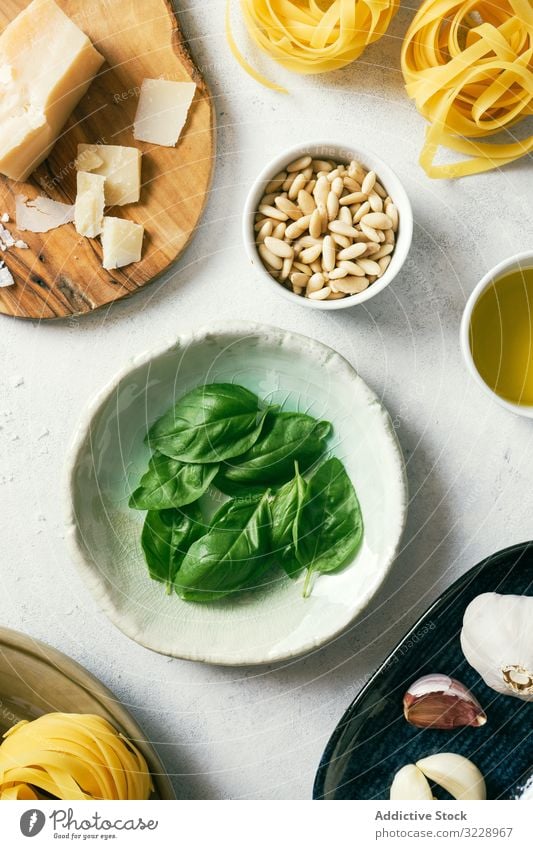Basilikumblätter und Zutaten für Pestosauce auf Tellern auf dem Tisch Bestandteil frisch grün farbenfroh Kraut Pinienkerne Parmesan Käse Küche Spätzle