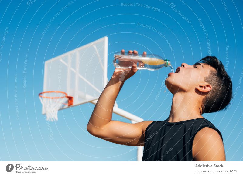 Junger Mann spielt auf Basketballplatz im Freien Trinkwasser Athlet Konkurrenz Sportgerät Erwachsener Erholung Aktion Ball Porträt aktiv Aktivität Asphalt