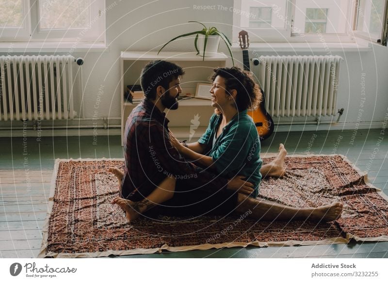 Liebespaar umarmt sich, während es auf dem Boden einer Wohnung sitzt Paar Umarmen Stock Appartement sitzen liebevoll Kuscheln Angebot lässig Lächeln Teppich