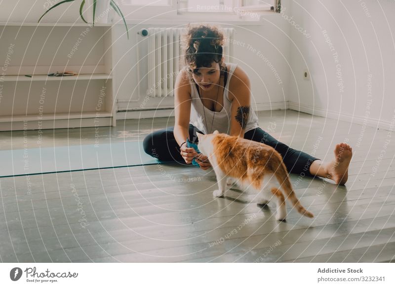 Entspannte Frau spielt zu Hause mit Katze auf dem Boden spielen heimwärts entspannt fürsorglich katzenhaft heimisch Appartement Stock Barfuß lässig modern
