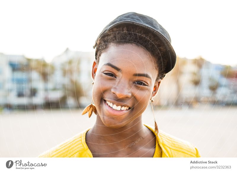 Fröhliche Frau lächelt in die Kamera stylisch Afroamerikaner Lächeln Jacke hell niedlich attraktiv positiv Gesundheit charmant jung hübsch modern heiter Lachen