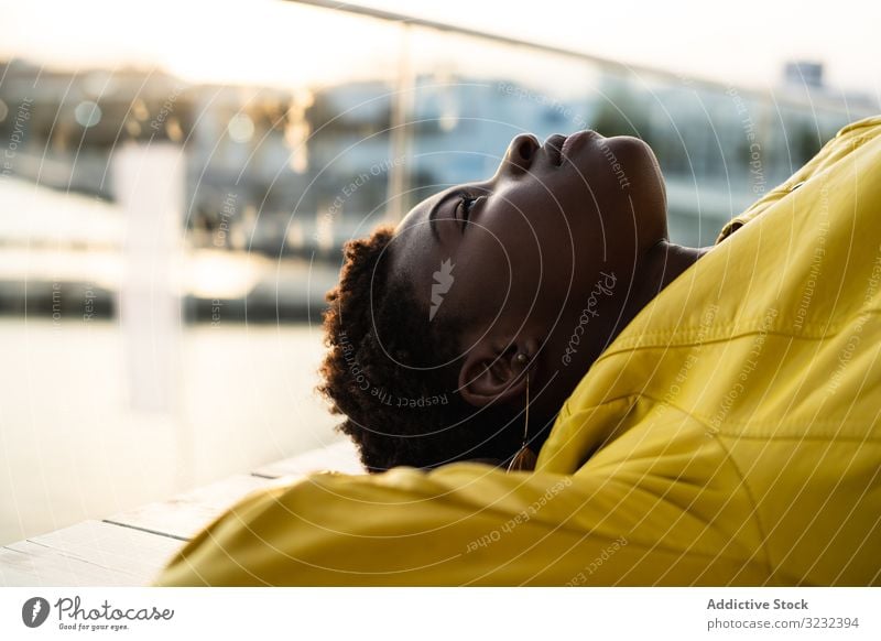 Frau chillt auf der Bank stylisch Kälte sich[Akk] entspannen modern klug hölzern Jacke Afroamerikaner jung cool trendy Glück Zeitgenosse Treffpunkt niedlich
