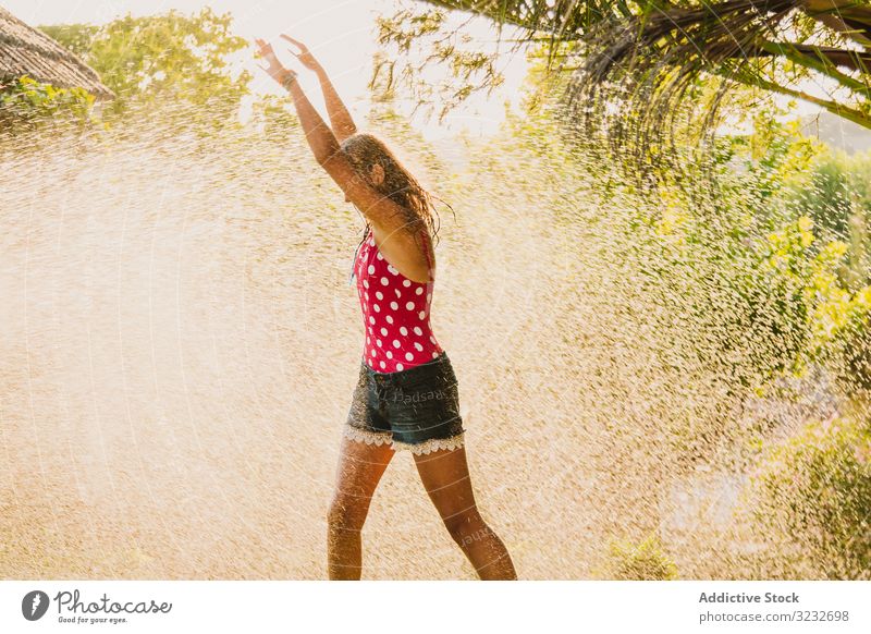 Fröhlicher Teenager hat Spaß mit Wasserstrahl Garten Düsenflugzeug Lachen Sommer Wochenende Mädchen aufgeregt Lifestyle ruhen sich[Akk] entspannen strömen