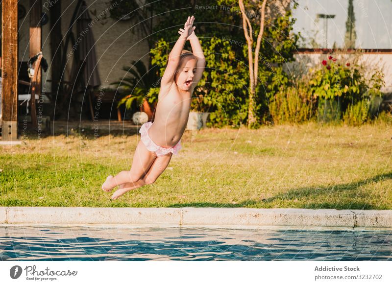 Fröhliches Mädchen springt in den Pool springen Wasser schreien angehobene Arme Spaß Hof spielen Kind wenig Hände hoch Frauenunterhose ohne Hemd Garten Urlaub