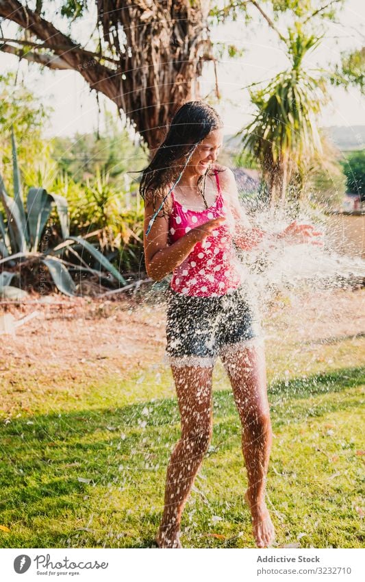 Fröhlicher Teenager hat Spaß mit Wasserstrahl Garten Düsenflugzeug Lachen Sommer Wochenende Mädchen aufgeregt Lifestyle ruhen sich[Akk] entspannen strömen