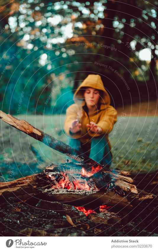 Reisende Frau wärmt Hände am Lagerfeuer auf Waldwiese warm ruhig Flamme nachdenken sich[Akk] entspannen Einsamkeit ruhen Windstille Stille Brennholz Freiheit