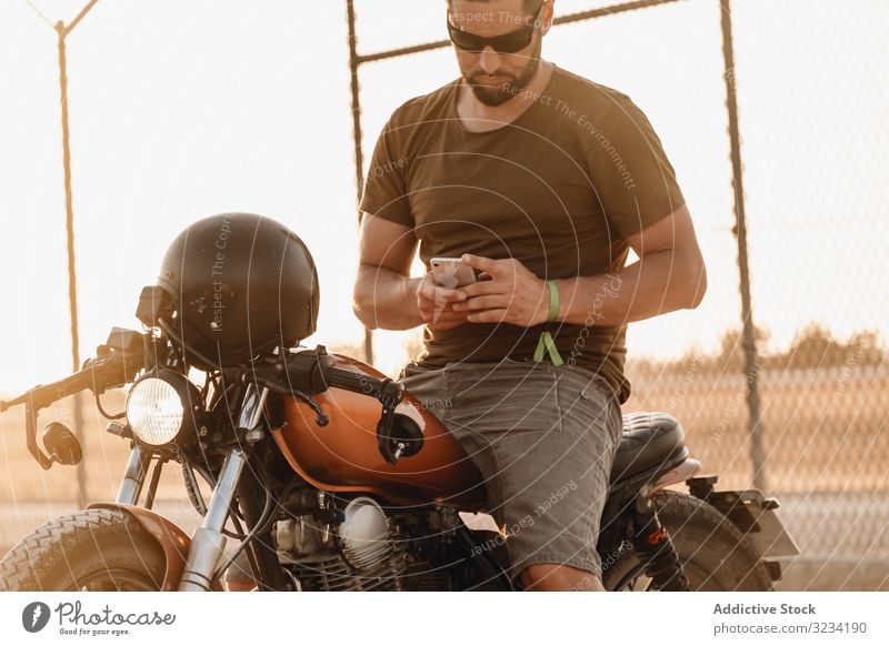 Porträt eines bärtigen Motorradfahrers mit Helm und Sonnenbrille auf seinem  Motorrad sitzend - ein lizenzfreies Stock Foto von Photocase