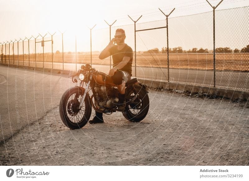Mann sitzt auf Motorrad und surft mobil Smartphone moto ruhen benutzend sprechend Surfen Sonnenbrille fokussiert wehmütig sitzen Mobile männlich Feld Verkehr
