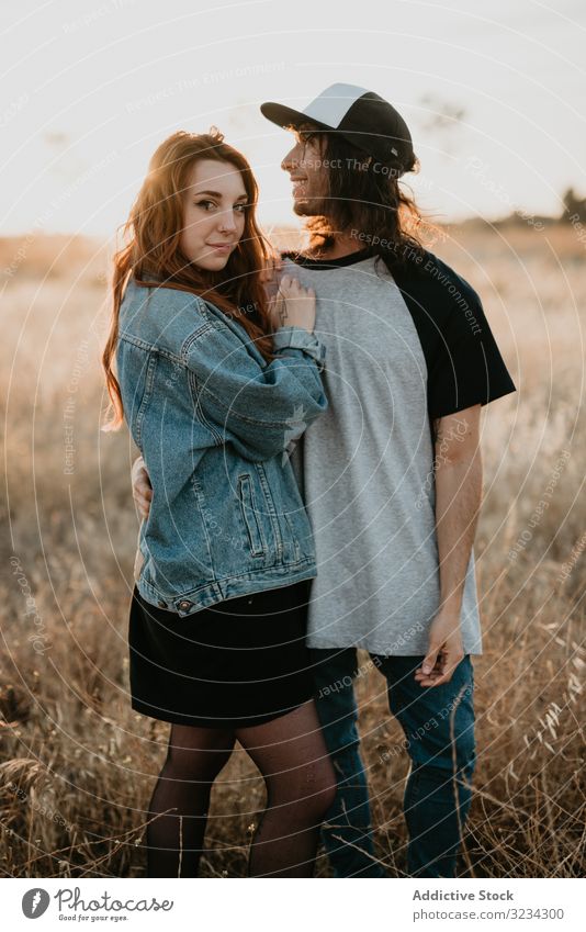 Hipster-Teenager-Paar, das sich auf dem Feld im Sonnenlicht verbindet ländlich Bonden Umarmen Sonnenuntergang Partnerschaft Sommer Generation romantisch