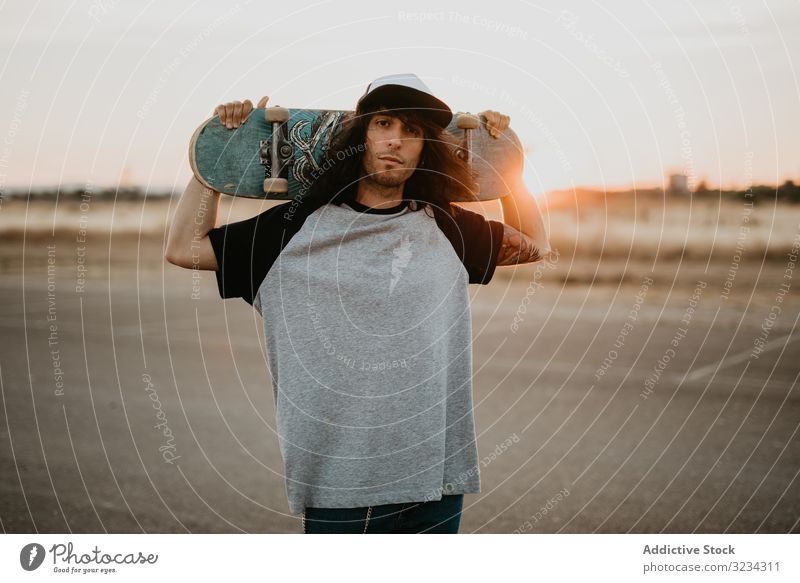 Cooler selbstbewusster Teenager mit Skateboard vor der Kamera Hipster cool Mann Stil tausendjährig ländlich Land Streetstyle Verschlussdeckel Generation