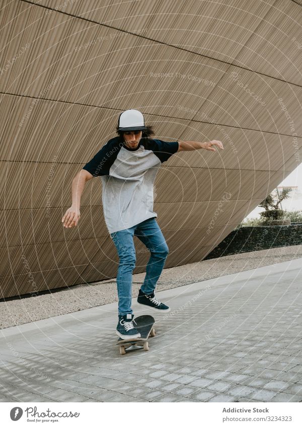 Sportlicher Teenager fährt Schlittschuh auf der Straße entlang der abfallenden Wand Mann Mitfahrgelegenheit Skateboard cool urban modern Gleichgewicht Skater