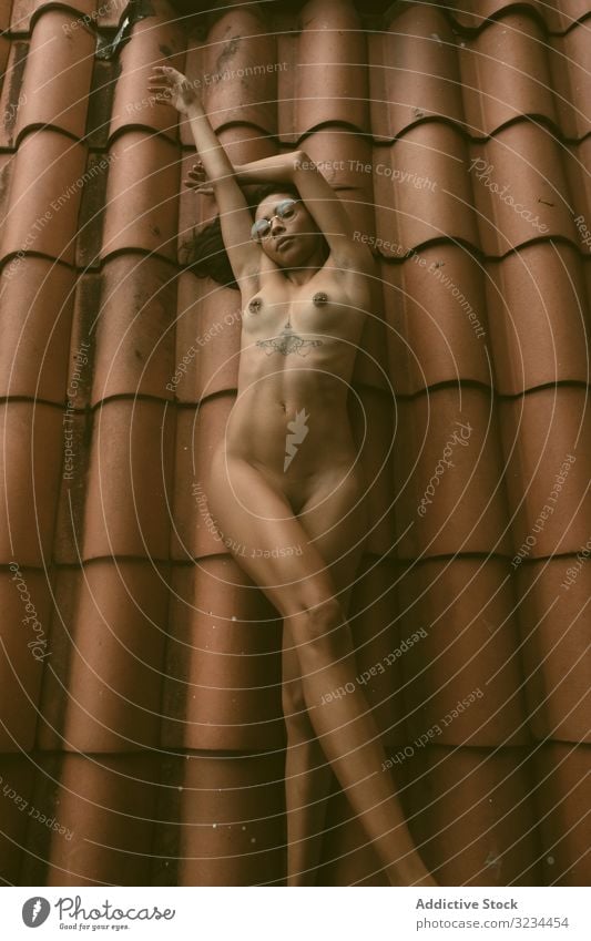 Nackte Frau auf dem Dach liegend nackt sinnlich angehobene Arme ethnisch gekachelt Haus jung Verlockung Körper ruhen sich[Akk] entspannen Brust brünett Dame