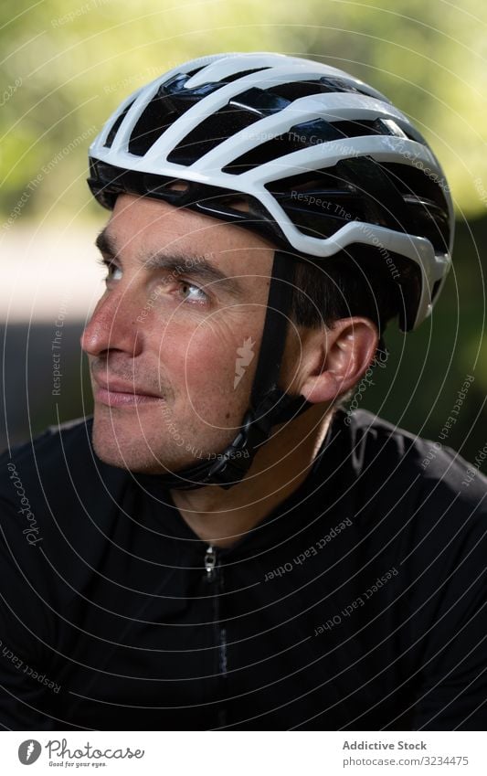 Positiver Radfahrer schaut im Park weg Training positiv Mann Lächeln Schutzhelm sonnig tagsüber Sport Sommer männlich Sicherheit froh zufrieden Erwachsener