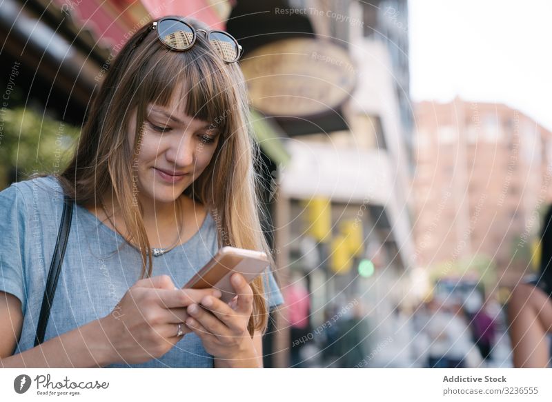 Frau mit Brille mit Smartphone im Freien Großstadt heiter lässig Sonnenbrille Straße Nachricht Lifestyle Tippen benutzend Mobile Apparatur SMS urban Antwort