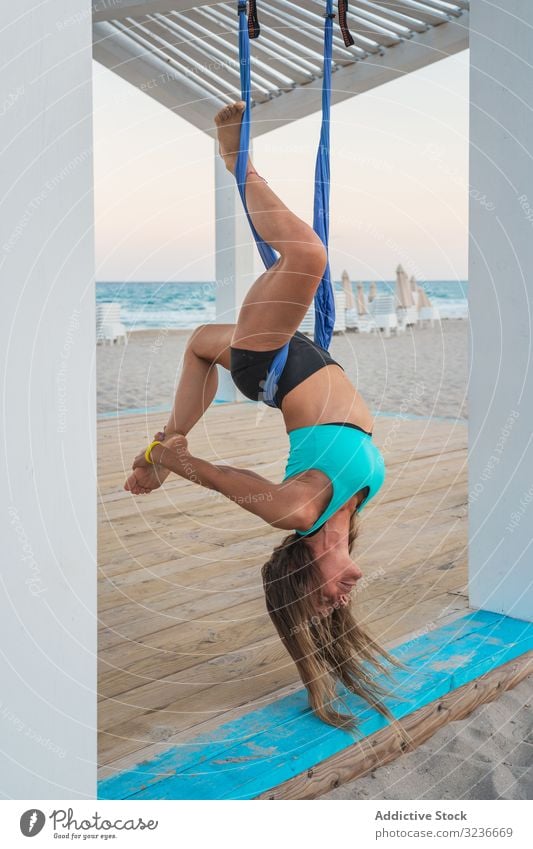 Entspannte Frau, die Luftyoga macht, den Kopf nach unten hängend und das Bein berührend Luft-Yoga herunterhängen Übung Gleichgewicht akrobatisch Fitness