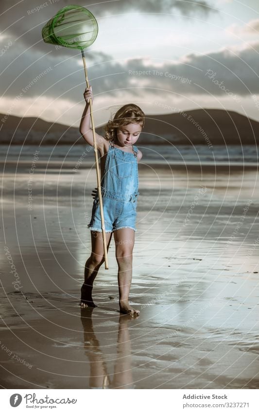 Kurioses Kind mit Schmetterlingsnetz läuft barfuss am nassen Ufer laufen Seeküste niedlich Kindheit Natur fangen Netz Aktivität wenig natürlich Küste Strand